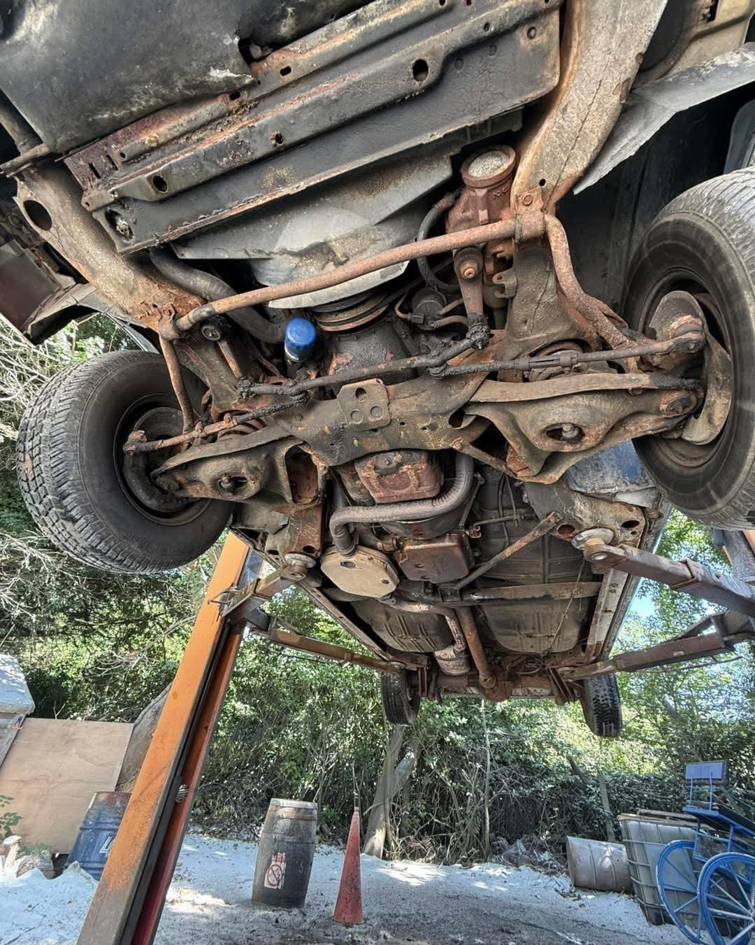 Classic car underside with corrosion across the subframe and floor