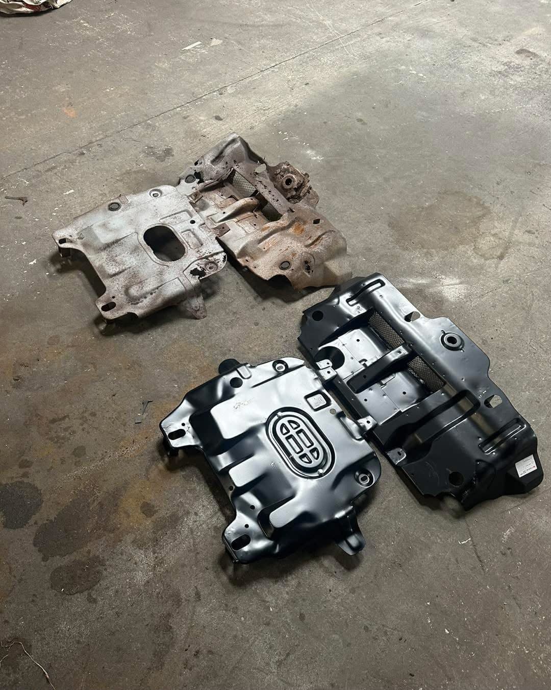Corroded original underbody plates beside workshop-made replacement plates